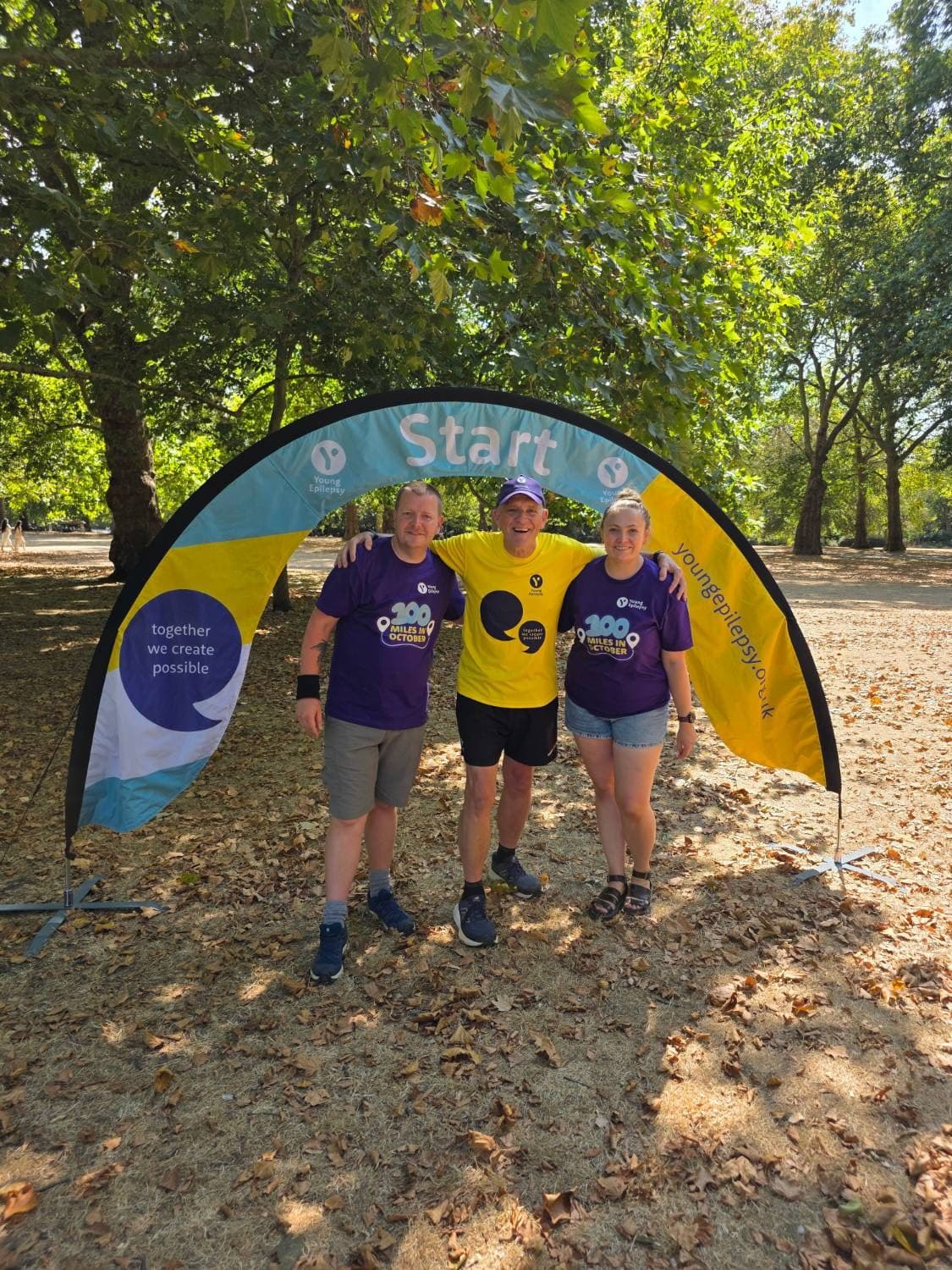Rory Coleman with two Young Epilepsy fundraisers under a Young Epilepsy start arch